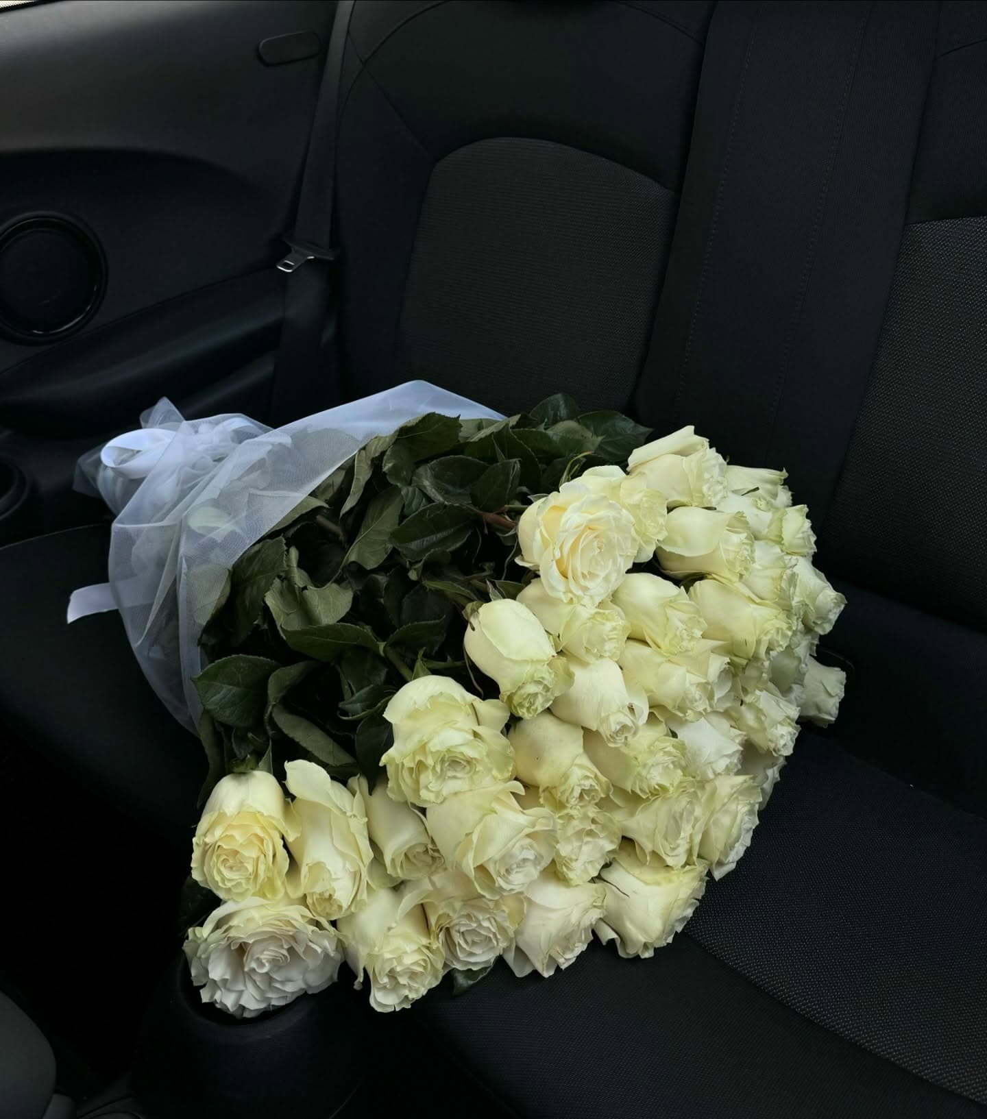 Ramo abundante de rosas blancas fotografiado cerca de un auto